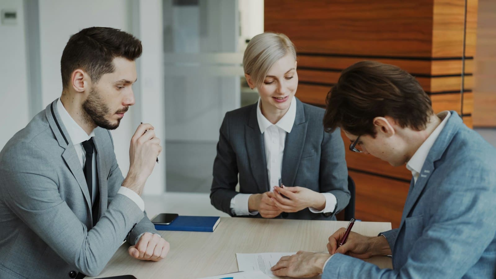 Business professionals signing a contract together at a conference table