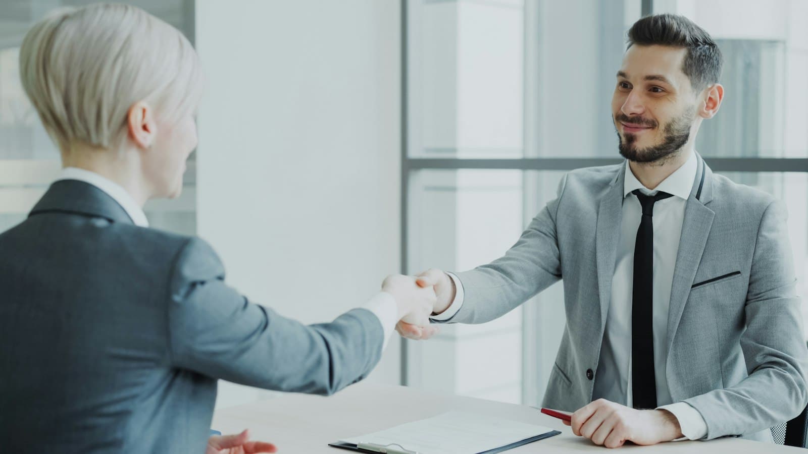 Two business professionals shaking hands in a modern office